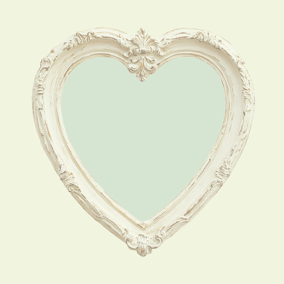 Achterzijde van een kaart met een pastelgroen hart in een witte barokke lijst, vintage stijl.