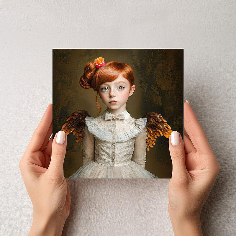 Mock-up van de Evi engelkaart, met een meisje in witte jurk en oranje-bruine engelenvleugels, vastgehouden door twee handen tegen een lichte achtergrond.