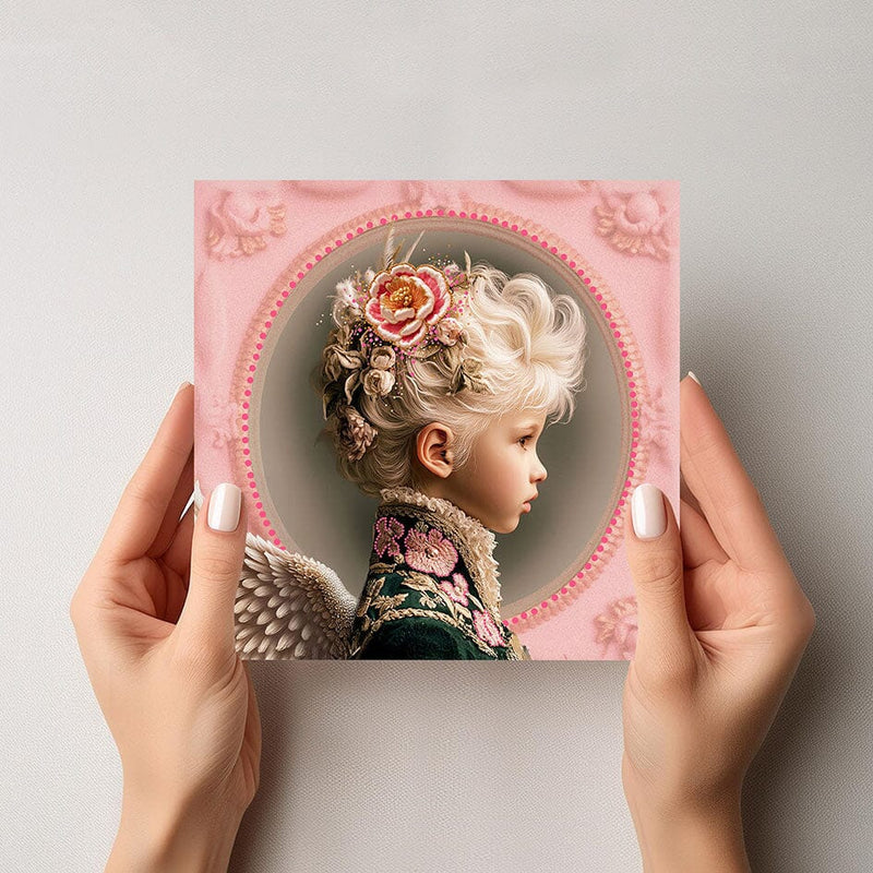 Mock-up van de Mozes engelkaart, met een jongen in barokke jas, roze rozen en zachte engelenvleugels, vastgehouden door twee handen tegen een lichte achtergrond.