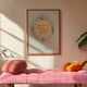 Ingelijste quote-poster boven roze bank in warm interieur